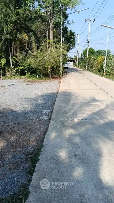 Scenic rural road with lush greenery and clear blue sky, ideal for peaceful living.