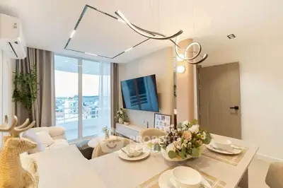 Modern living room with elegant dining area and large TV, featuring stylish lighting and panoramic window views.