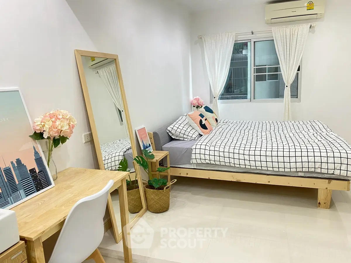 Modern bedroom with stylish decor, featuring a cozy bed, desk, and large mirror, perfect for urban living.