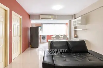 Modern living room with black leather sofa and open kitchen layout