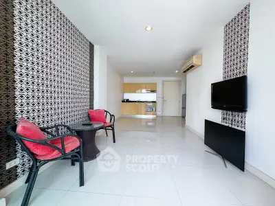 Modern living room with stylish decor and open kitchen layout, featuring sleek furniture and wall-mounted TV.