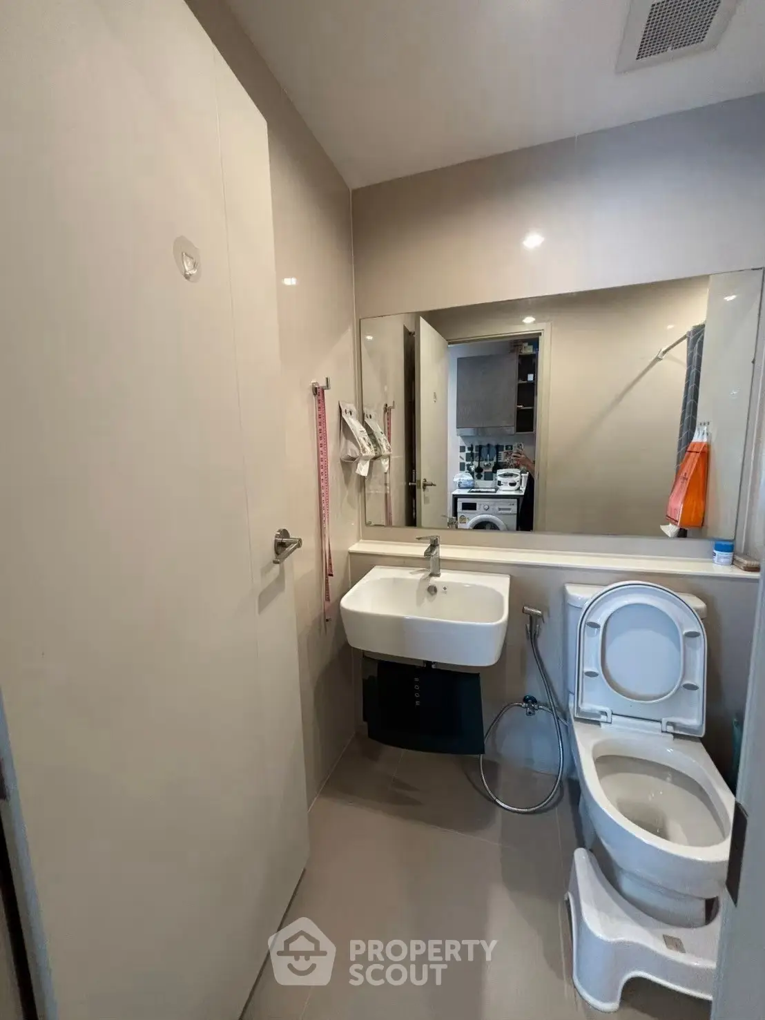 Modern bathroom with sleek design and large mirror, featuring a toilet and sink.