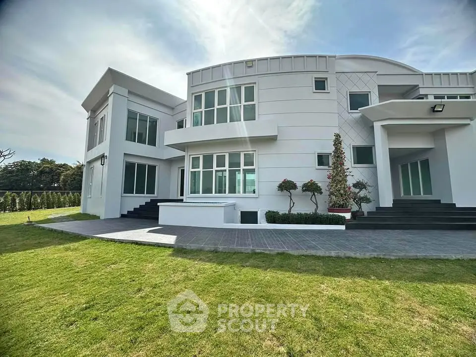 Luxurious modern white villa with expansive lawn and unique architectural design.