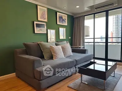 Stylish living room with green accent wall and modern sofa in a high-rise apartment.