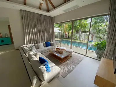 Luxurious living room with pool view, featuring elegant decor and abundant natural light.
