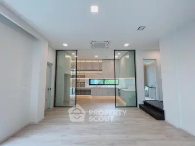 Spacious modern living room with glass partition and sleek kitchen design