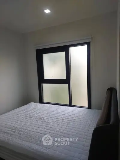 Cozy bedroom with large window and modern bed frame, perfect for relaxation and comfort.