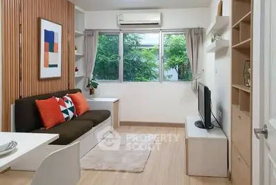 Modern living room with stylish decor and large window offering lush garden view.