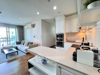 Spacious open-plan living room and kitchen with modern appliances and balcony view.