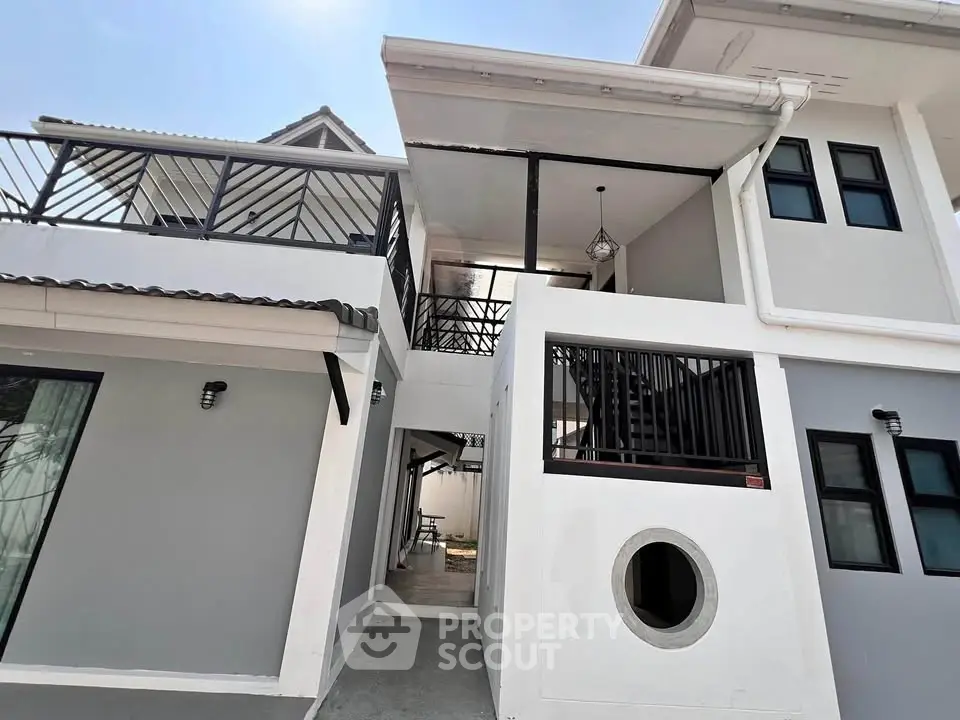 Modern multi-level white house with unique architectural design and spacious balconies.