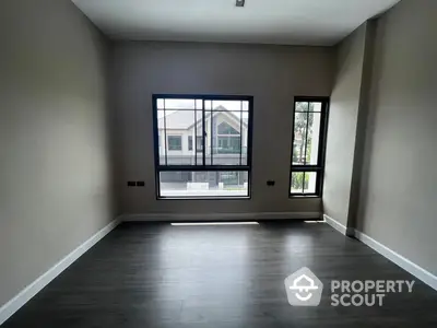 Spacious and modern living room with large windows allowing ample natural light, featuring elegant dark hardwood floors and neutral wall colors, perfect for personalizing your new home.