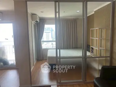Modern bedroom with city view, wooden flooring, and glass partition in a high-rise apartment.