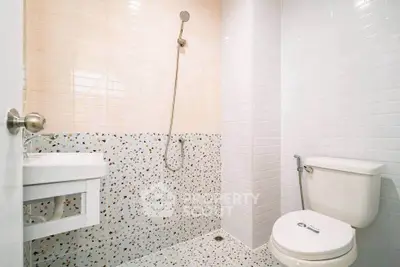 Modern minimalist bathroom with terrazzo flooring and sleek white tiles.