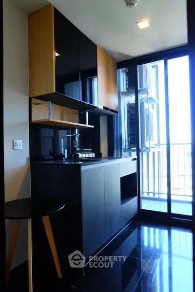 Modern kitchen with sleek black cabinetry and floor-to-ceiling windows offering abundant natural light.