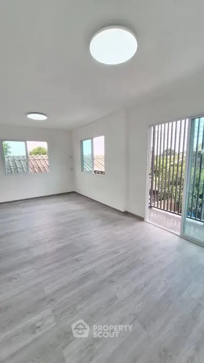 Spacious empty room with large windows and sliding glass door opening to a balcony.