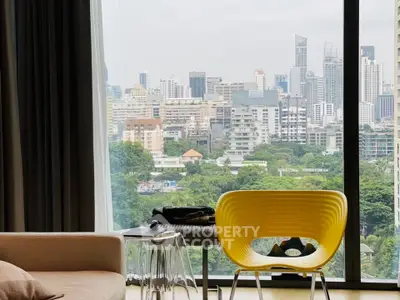 Modern living room with stunning city view through large window, featuring stylish yellow chair and elegant decor.