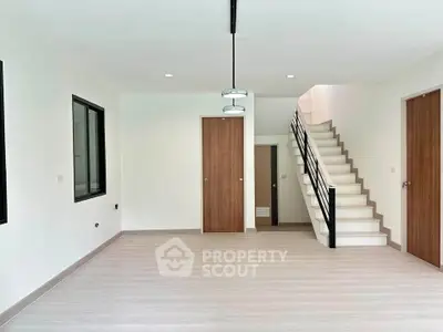 Spacious modern living room with staircase and wooden flooring, ideal for contemporary living.
