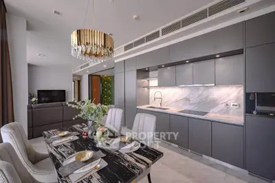 Luxurious modern kitchen and dining area with sleek cabinetry and elegant chandelier.