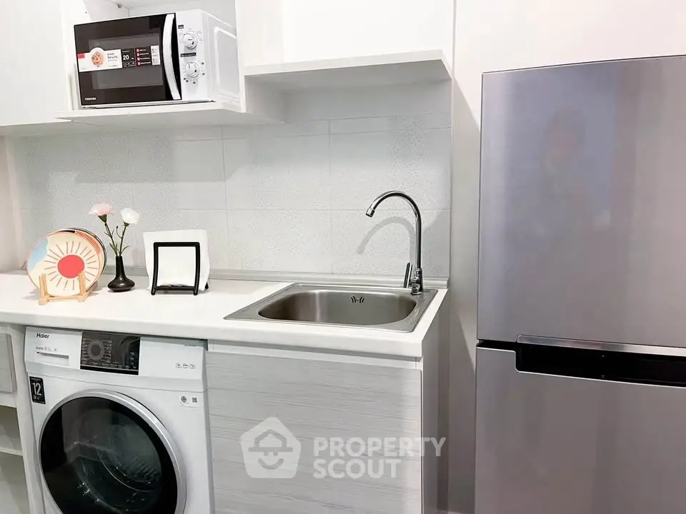 Modern kitchen with sleek appliances including washing machine and fridge.