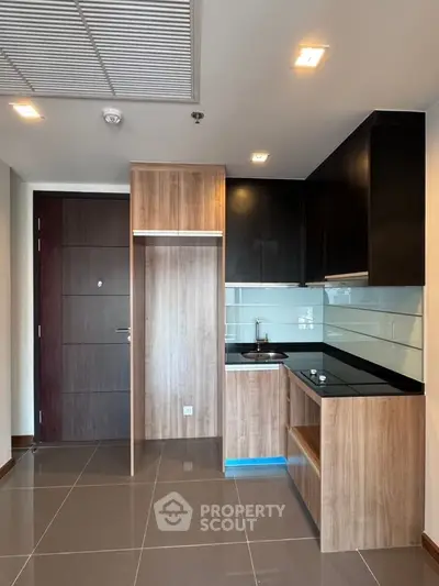 Modern kitchen with sleek cabinetry and glass backsplash in a compact apartment setting.