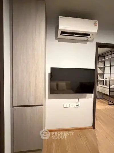 Modern living room with air conditioning and wall-mounted TV, featuring sleek wooden flooring and minimalist design.