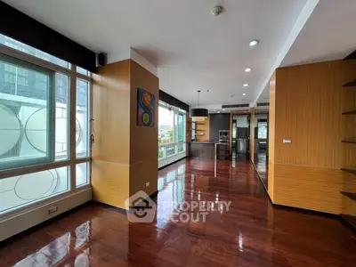 Spacious modern living room with open kitchen and wooden flooring in urban apartment.