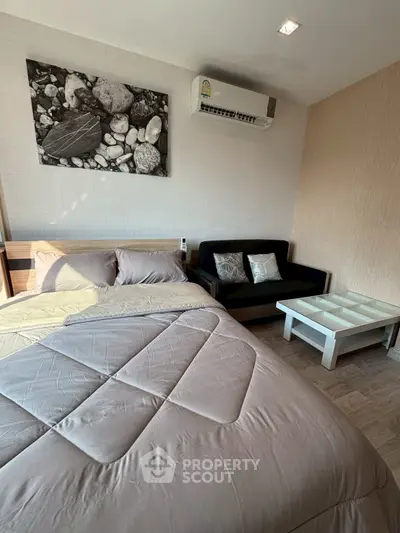 Cozy bedroom with modern decor and air conditioning, featuring a comfortable bed and stylish sofa.