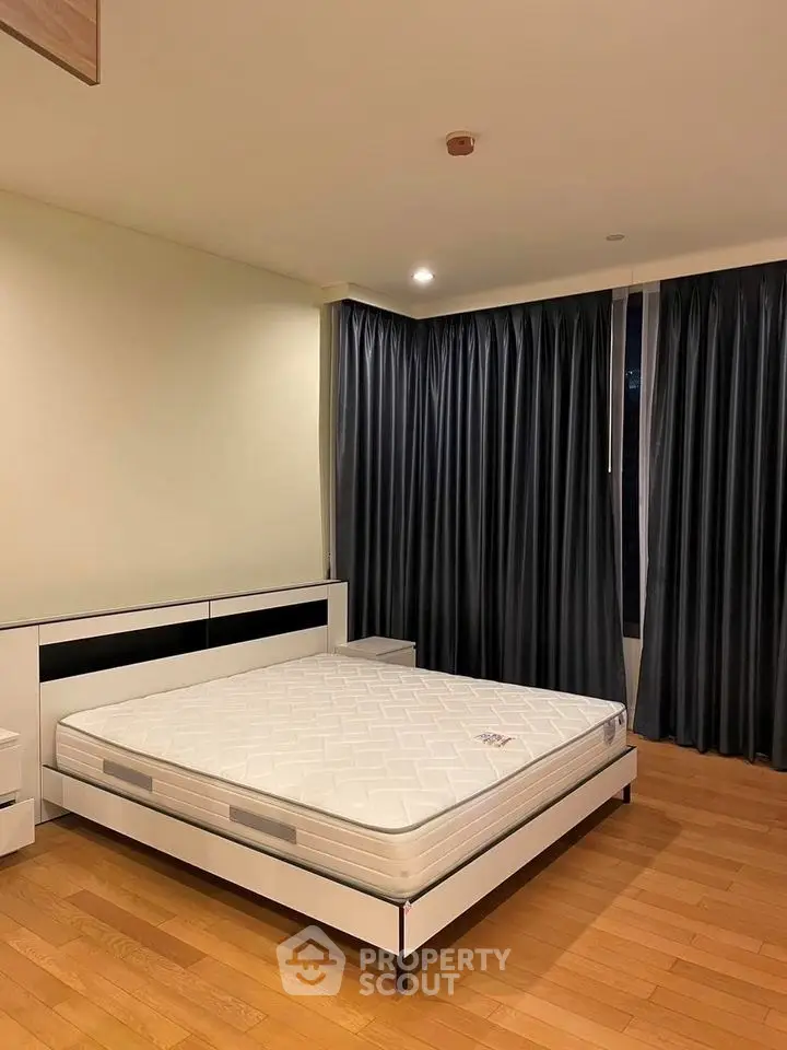 Spacious bedroom with modern furnishings and large windows for natural light.