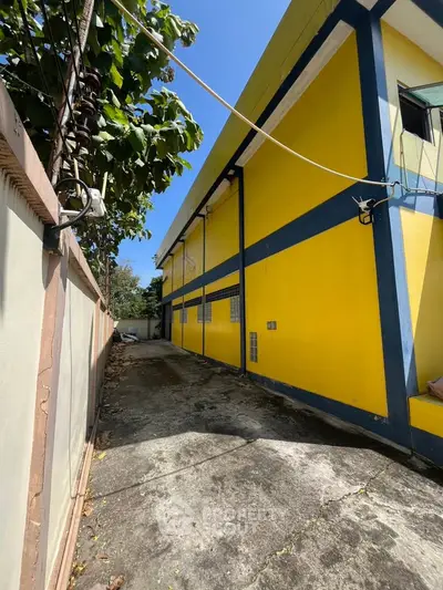 Vibrant yellow building exterior with blue accents and spacious driveway under clear blue sky.
