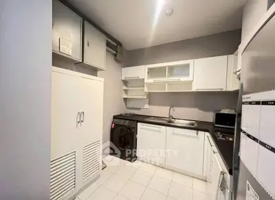 Modern kitchen with sleek white cabinets and integrated appliances in a compact layout.