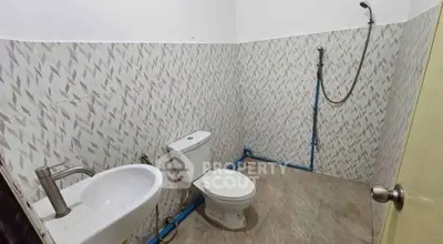 Simple bathroom with tiled walls, toilet, sink, and shower area.