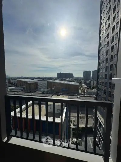 Stunning urban view from a high-rise balcony with cityscape and sunlit sky.
