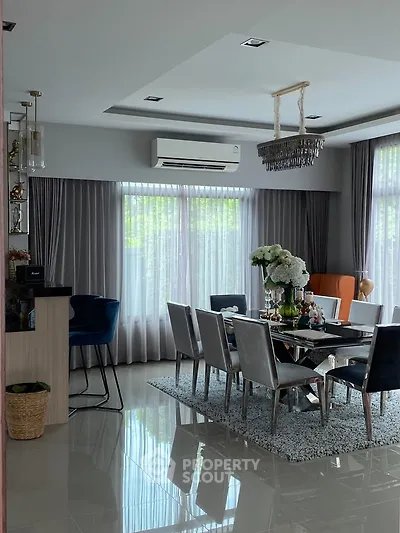 Elegant dining room with modern decor, large windows, and stylish chandelier in a spacious home.
