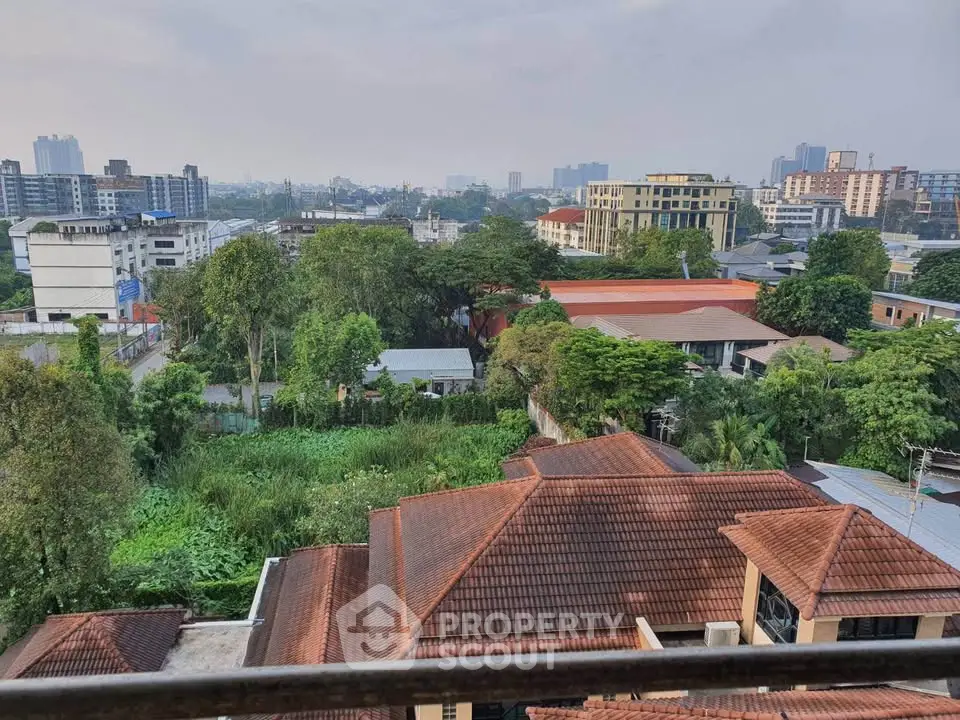 Stunning cityscape view from a high-rise balcony overlooking lush greenery and urban skyline.