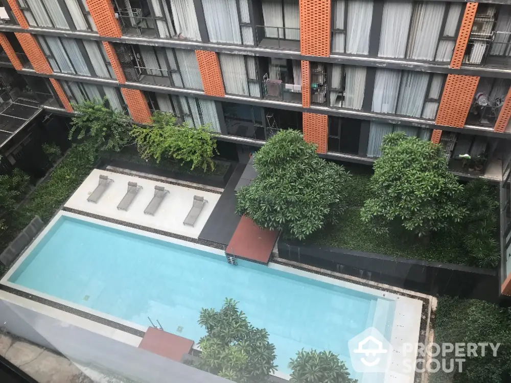 Modern apartment building with a luxurious swimming pool and lush greenery view.