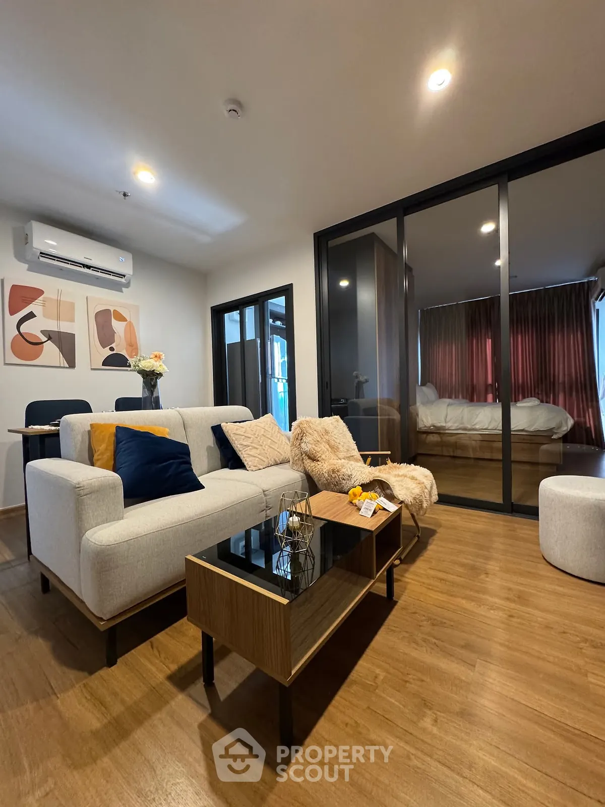 Modern living room with cozy decor and glass partition to bedroom