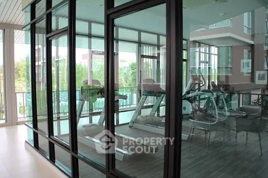 Modern gym with glass walls and state-of-the-art equipment in a luxury residential building.