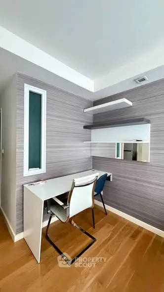 Modern study room with sleek desk and chairs, featuring stylish wall shelves and wooden flooring.