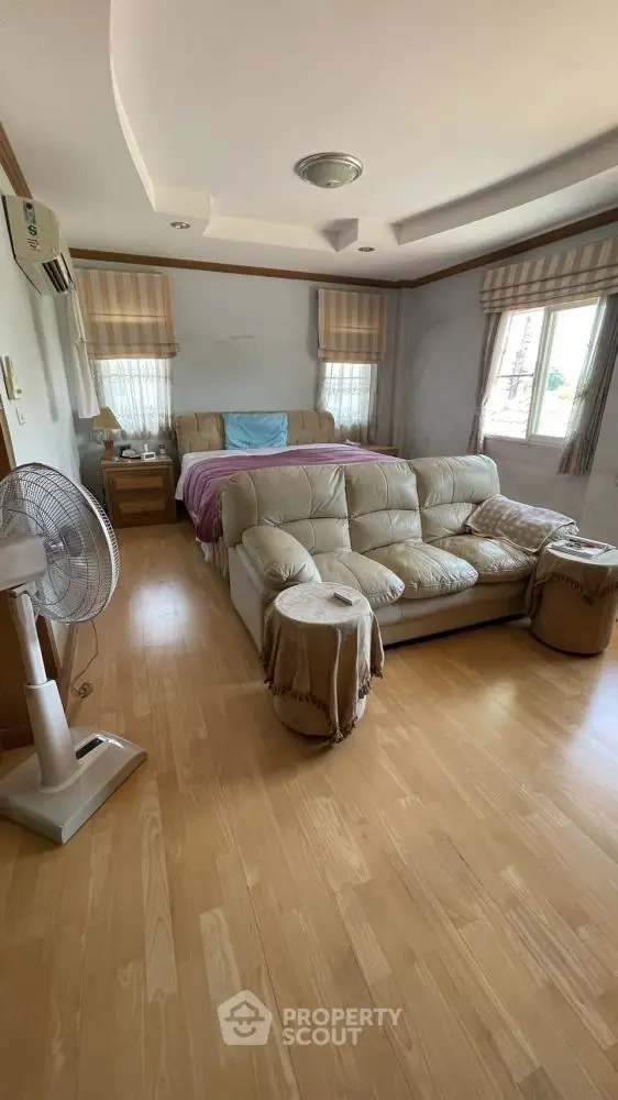Spacious bedroom with cozy seating area and natural light