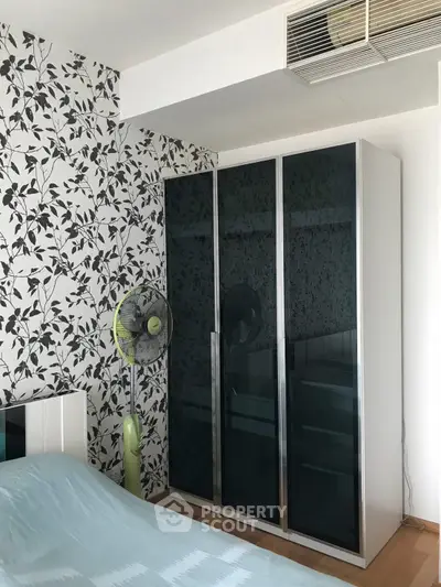 Stylish bedroom with modern wardrobe and floral wallpaper accent wall.