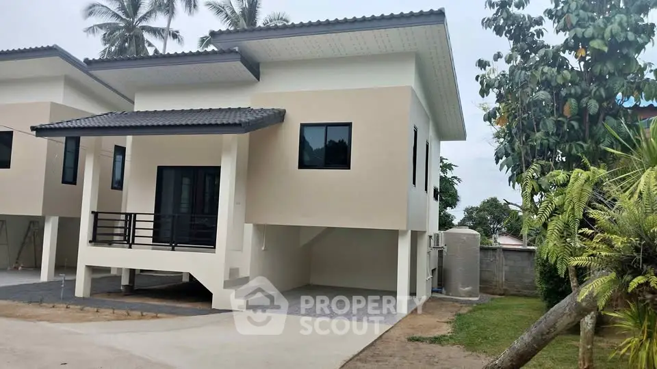 Modern two-story house with sleek design and spacious driveway in a tropical setting.