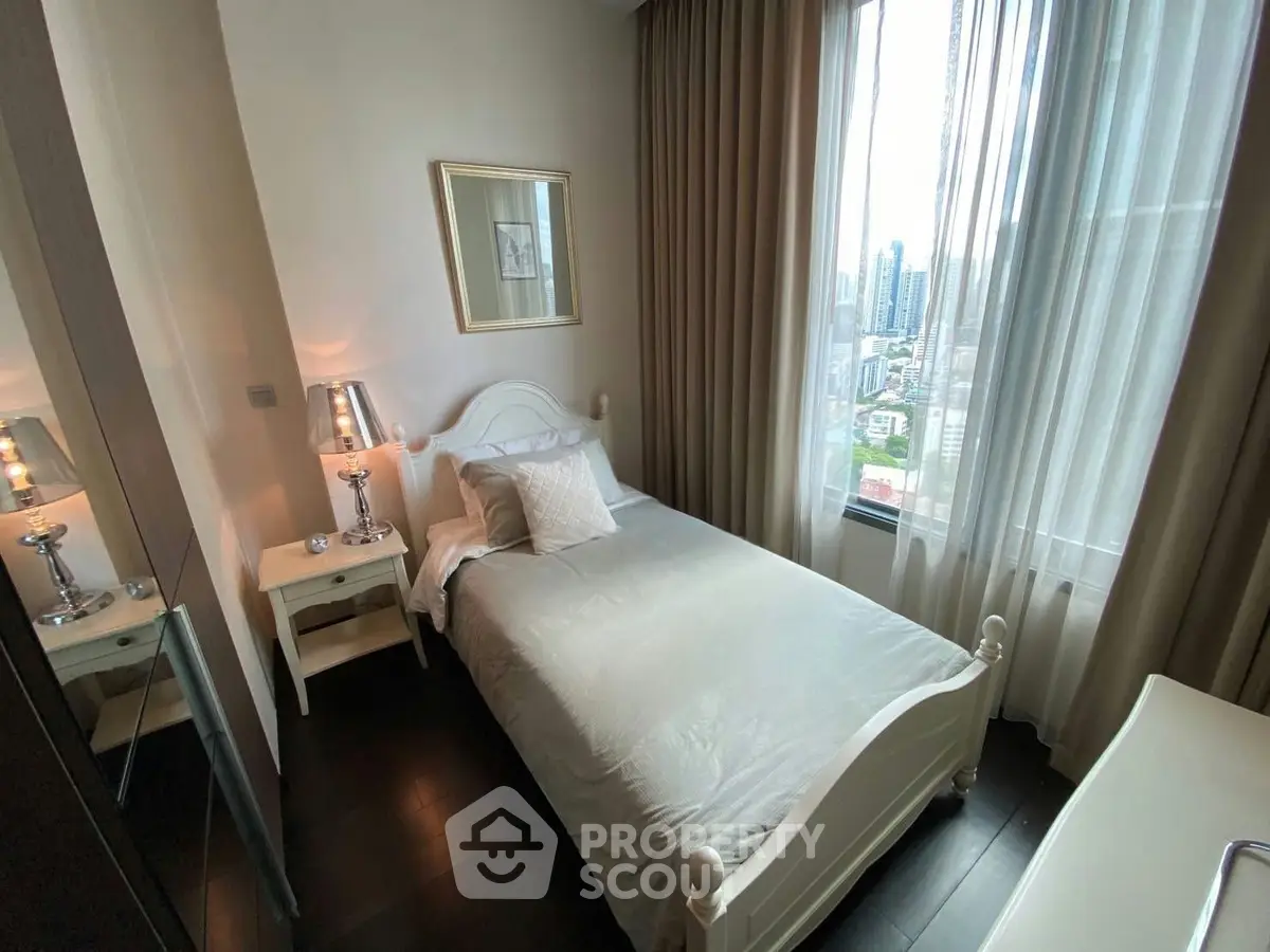 Cozy bedroom with city view, featuring elegant decor and natural light through large windows.