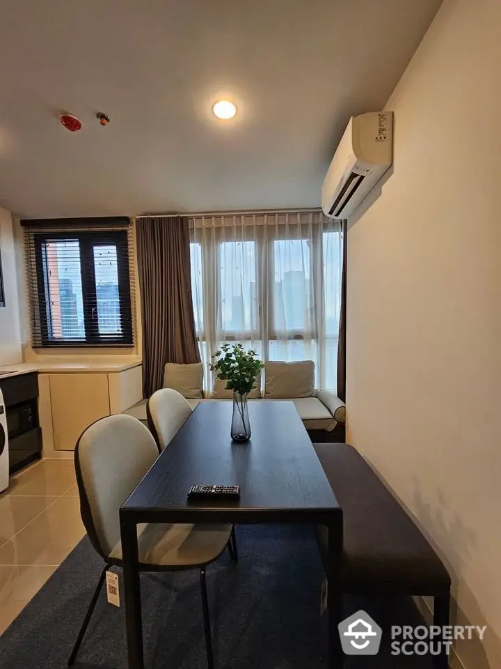 Modern dining area with sleek table and chairs, adjacent to cozy living space and large windows.