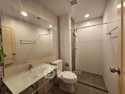 Modern bathroom with glass sink and walk-in shower in sleek apartment.