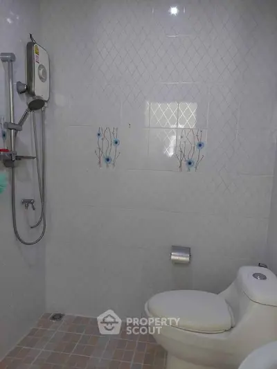 Modern bathroom with shower and toilet in a tiled setting