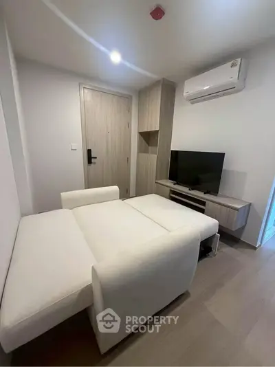 Modern living room with sleek furniture and air conditioning in a compact apartment.
