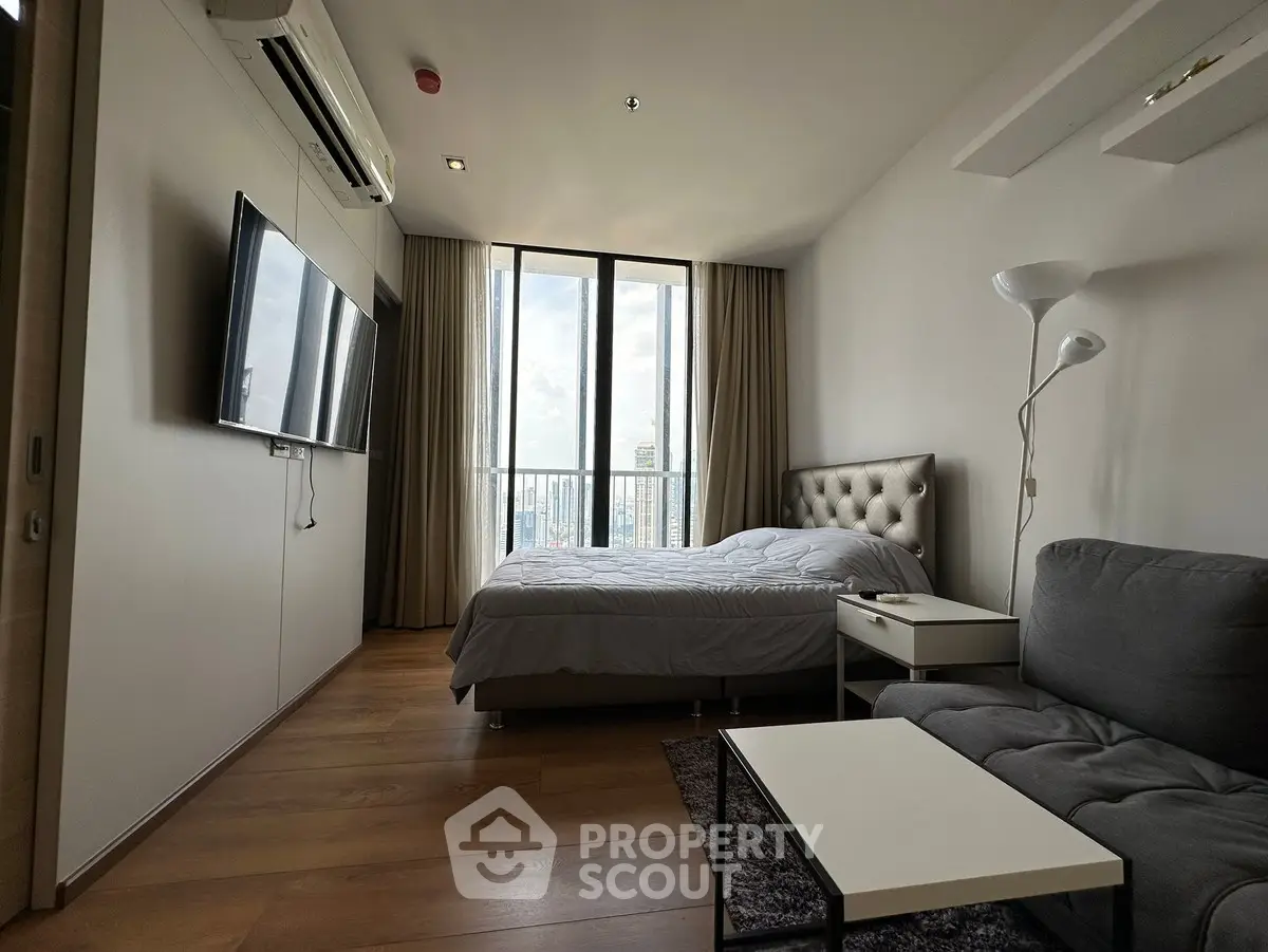 Modern bedroom with large window and city view, featuring stylish furniture and cozy ambiance.