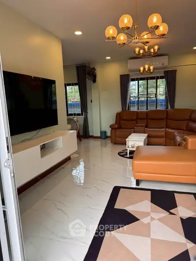 Spacious living room with modern decor and large TV, featuring elegant lighting and comfortable seating.