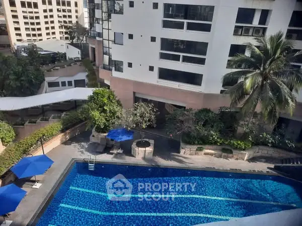 Luxurious apartment complex with stunning pool view and lush greenery.