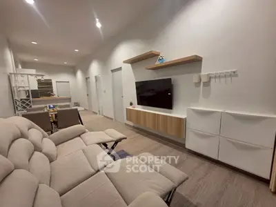 Modern living room with sleek furniture and wall-mounted TV in a spacious open layout.